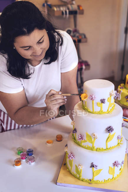 Konditor dekoriert geschichteten Kuchen mit Blumen — Stockfoto