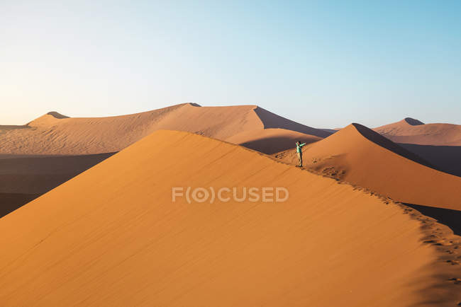 Namibia, Namib Desert, Sossusvlei, Woman with raised arms on Dune at sunrise — Stock Photo