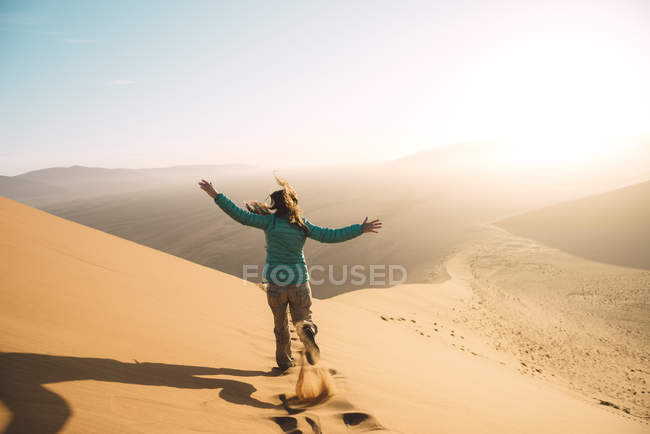 Namibia, Namib Desert, Sossusvlei, Woman running down the Dune at sunrise — Stock Photo