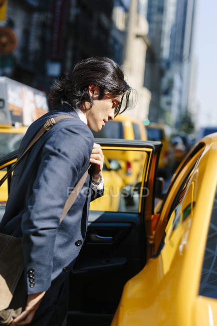 Asiático hombre de negocios entrar un taxi - foto de stock