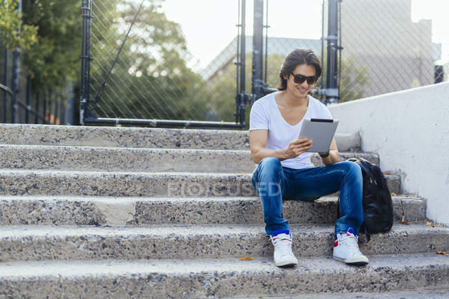 Man sitting on steps using digital tablet — Stock Photo