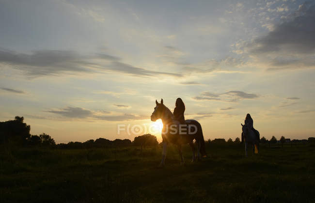 Young women riding into the sunset — Stock Photo