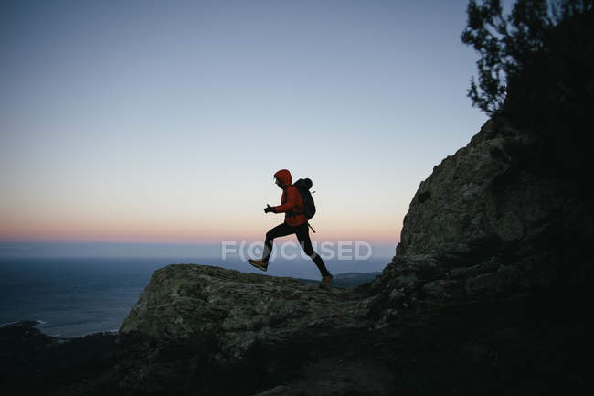 Mujer senderismo al atardecer en las montañas - foto de stock