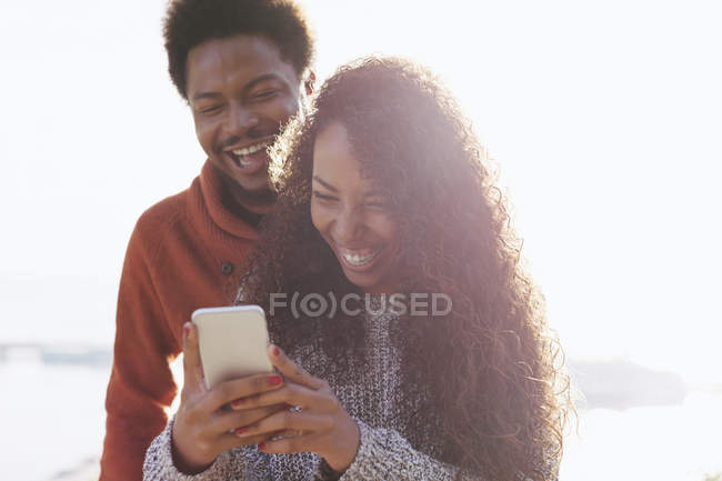 Ritratto di giovane coppia felice con smartphone alla retroilluminazione — Foto stock