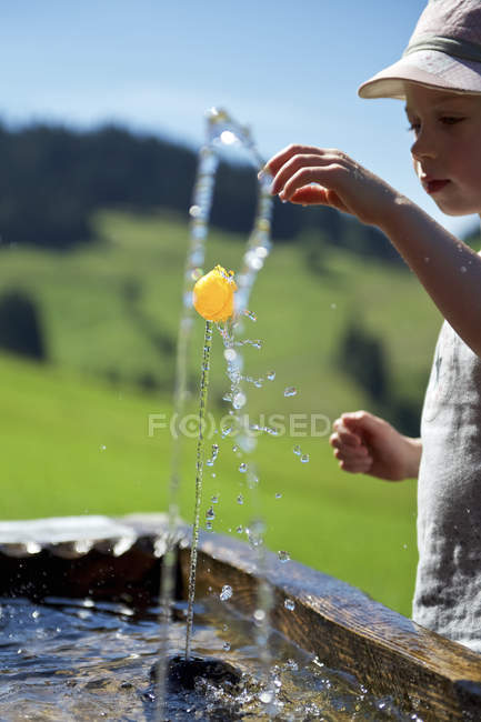 Ragazzo che gioca con una pallina alla fontana — Foto stock