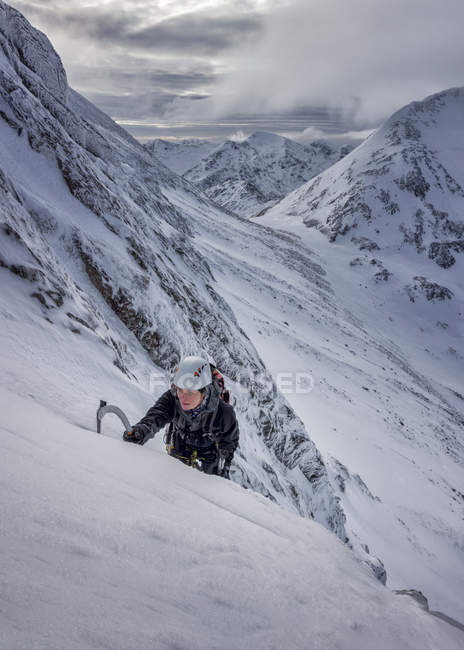 Reino Unido, Escocia, Glencoe, West Face Aonach Mor, mujer escalando hielo en montañas cubiertas de nieve - foto de stock