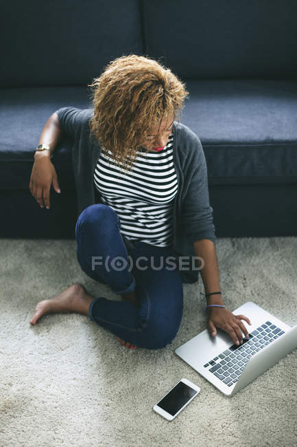 Woman sitting on carpet and using laptop — Stock Photo