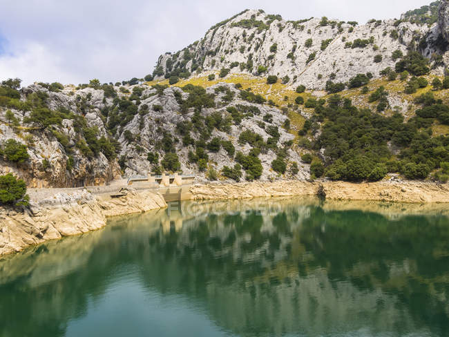 Испания, Озил, вид на Серра-де-Трамунтана, водохранилище Горг и вода против камней — стоковое фото