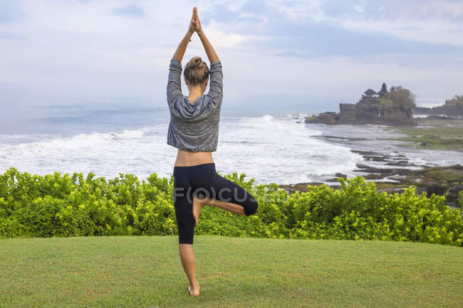 Indonesia, Bali, Tanah Lot, donna che pratica yoga sulla costa — Foto stock