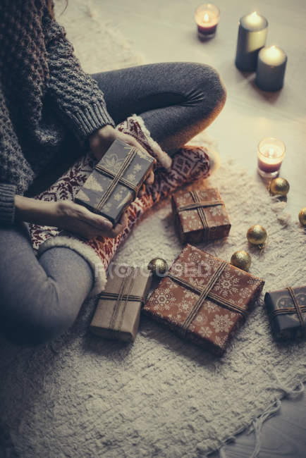 Mujer sentada con regalos de Navidad en la alfombra - foto de stock