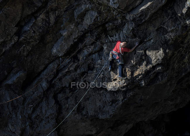 Man climbing on rock at Mother Carey's Kitchen, Pembroke, Regno Unito — Foto stock