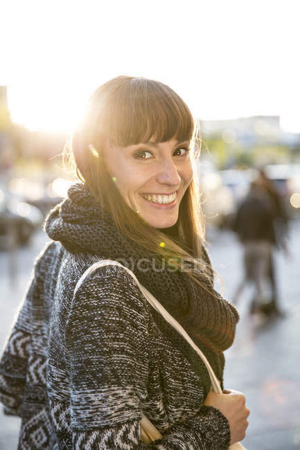 Retrato de uma jovem mulher sorridente olhando por cima do ombro — Fotografia de Stock