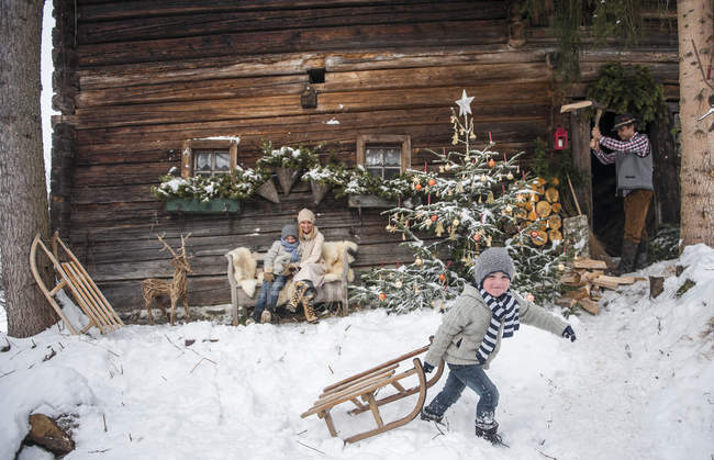 Austria, Altenmarkt-Zauchensee, family in front of farmhouse at Christmas time — Stock Photo