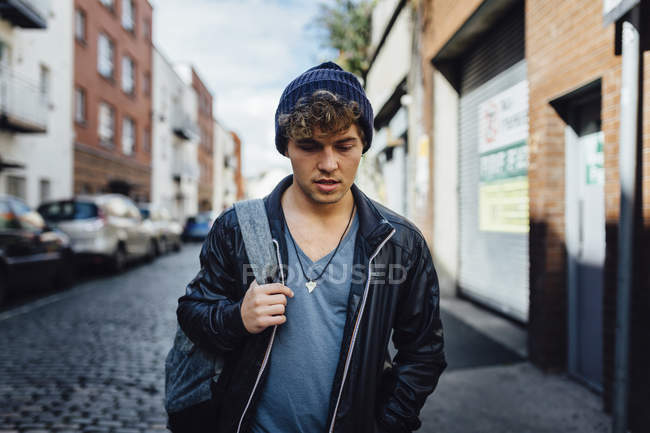 Ireland, Dublin, young man walking on the street with a backpack — Stock Photo