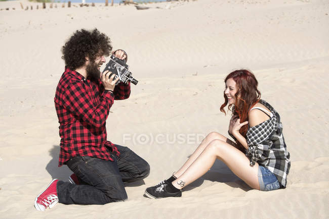 Молодий чоловік, що зйомки своєї подруги на пляжі — стокове фото