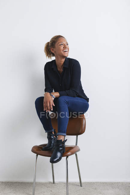 Woman sitting on backrest of chair — background, Jeans - Stock Photo |  #178194704