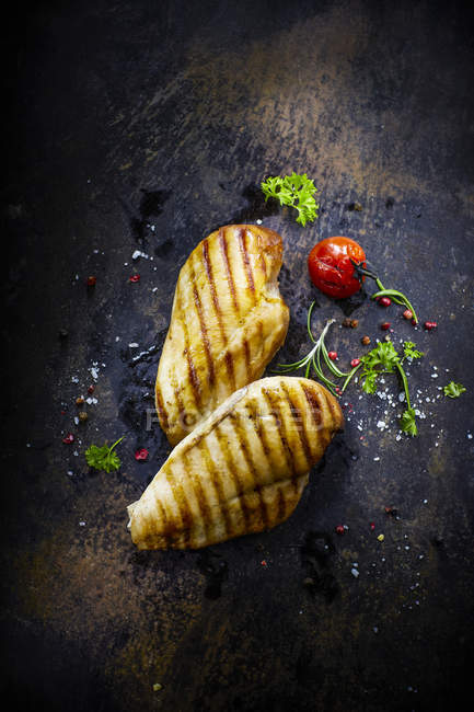 Filete de pollo con tomate cherry, chile y pimienta en la superficie de madera oscura - foto de stock