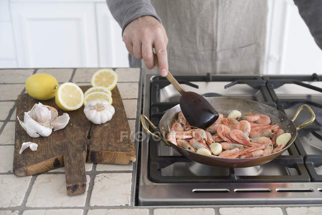 Man frying shrimps in pan — Stock Photo