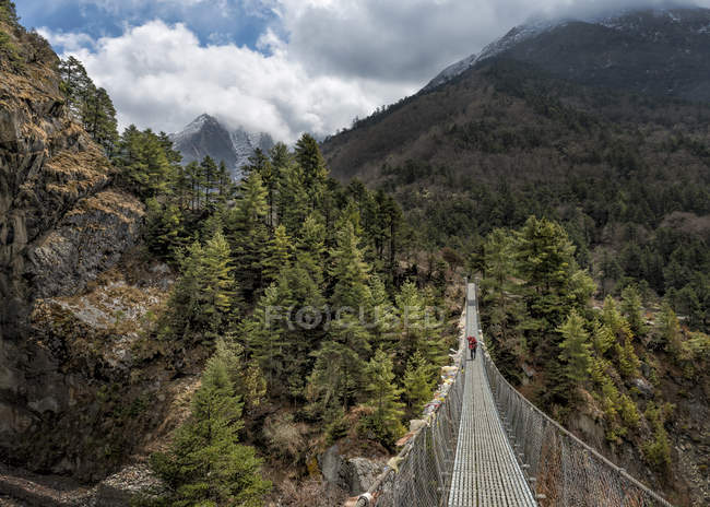 Nepal, Himalaya, Khumbu, trekker on footbridge in the mountains — Stock Photo