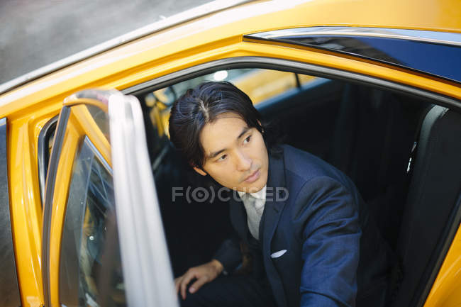 Asiático hombre de negocios entrar un taxi - foto de stock