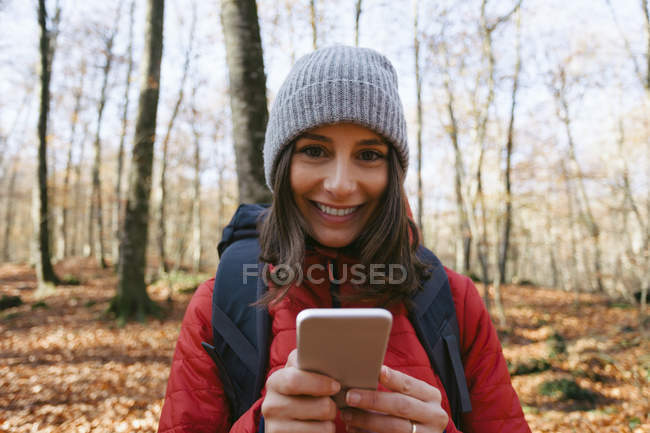 Іспанії, Каталонія, Жирони, портрет усміхнене жіночий мандрівного в ліс з мобільного телефону — стокове фото