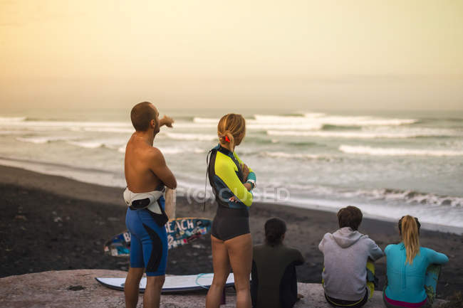 Indonesia, Bali, surfers resting on beach looking at view at twilight — Stock Photo