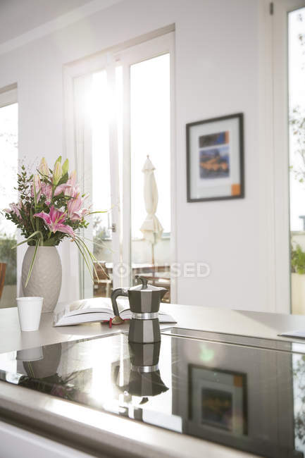 Bunch of flowers and coffee maker on oven in kitchen block — Stock Photo