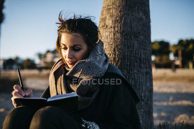 Frau schreibt im Winter am Strand in Notizbuch — Stockfoto