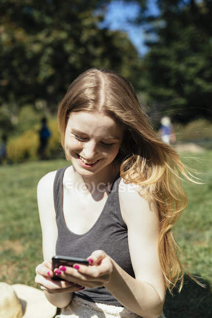 Mujer joven revisando el teléfono en el parque - foto de stock