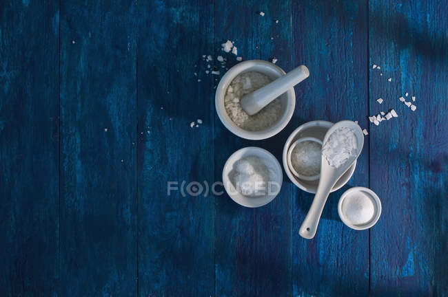 Cuencos de diferentes tipos de sal sobre madera azul - foto de stock