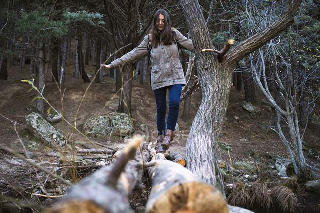 Молодая женщина, переходящая мост из стволов деревьев — стоковое фото