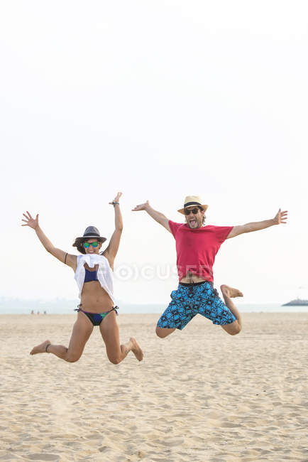 Spain, Cadiz, El Puerto de Santa Maria, Couple jumping on the beach — Stock Photo