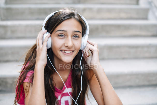Portrait of smiling teenage girl listening music with headphones — Stock Photo