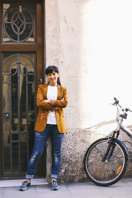 Mujer con bicicleta de pie en la entrada de la casa - foto de stock