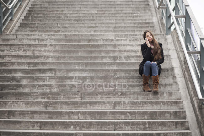 Jovem mulher sentada na escada de telefone com smartphone — Fotografia de Stock