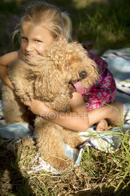 Bonne fille étreignant chien sur la couverture — Photo de stock