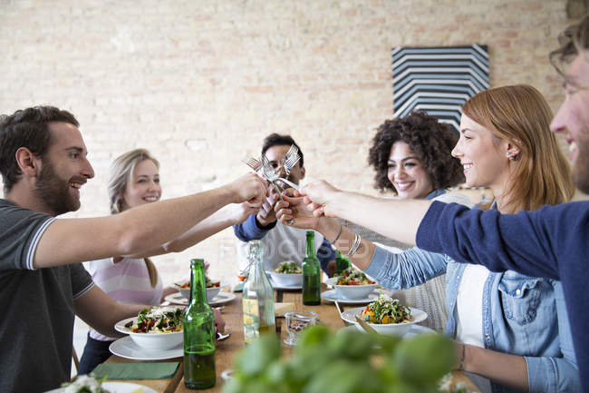 Happy friends eating together at table — Stock Photo