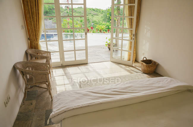 Daytime view of villa bedroom with opened doors to swimming pool — Stock Photo