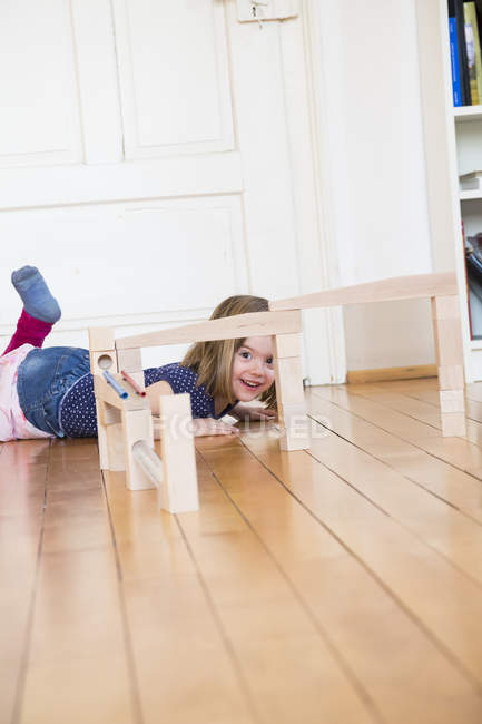 Bambina sdraiata sul pavimento dietro la corsa di marmo — Foto stock