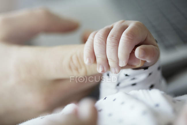 Primer plano del bebé sosteniendo el dedo del padre - foto de stock
