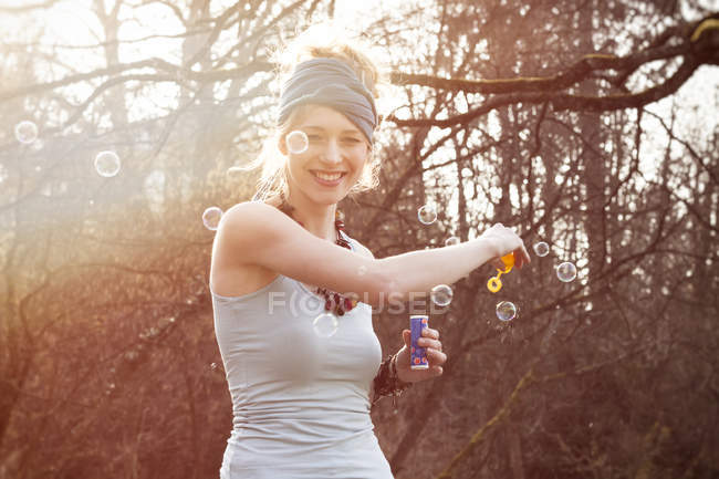 Sorrindo jovem mulher fazendo bolhas de sabão — Fotografia de Stock