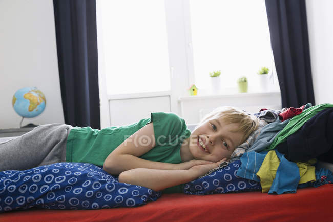 Sonriente chico acostado en la cama mirando a la cámara - foto de stock