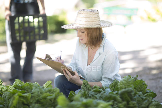 Giardiniere donna scrittura sugli appunti — Foto stock