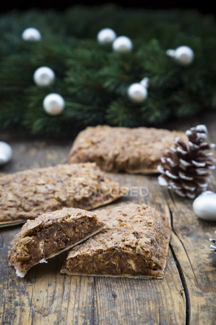Sliced Nuremberg gingerbread on wooden surface with christmas decor — Stock Photo