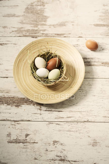 Easter nest with eggs in wooden bowl on shabby wood — Stock Photo