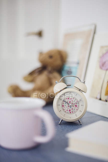 Floral pattern alarm clock on night table in girl's room — Stock Photo