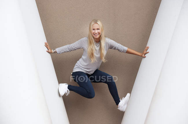 Ritratto di adolescente bionda sorridente tra colonne di cemento — Foto stock