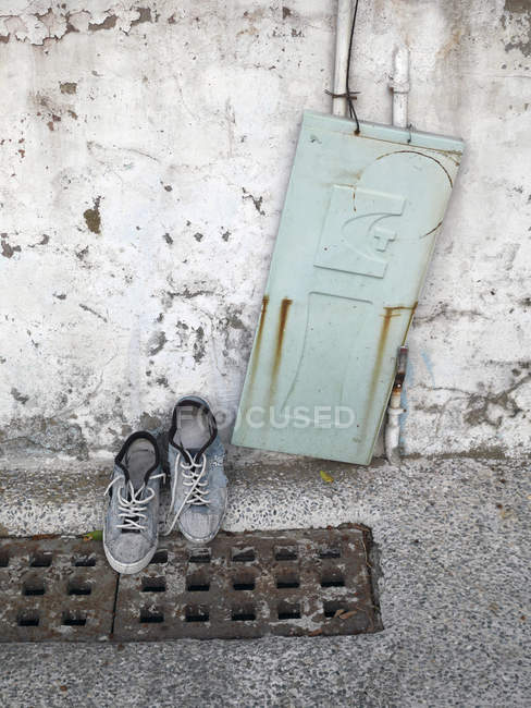 Taiwan, paire de chaussures sur le couvercle du ravin et une vieille porte en métal appuyée sur un mur — Photo de stock