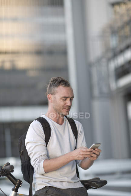 Blonder Mann auf Fahrrad mit Smartphone — Stockfoto