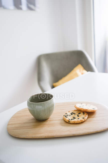 Tablero de bambú con tazón de té verde japonés y dos galletas de arroz - foto de stock